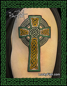 A Celtic cross tattoo design shown on skin, with green and gold details and a decorative border. The image includes the branding text Luckyfish.