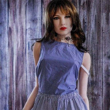 Upper body view of a silicone sex doll with brown hair wearing a blue striped outfit and jewelry against a wooden wall