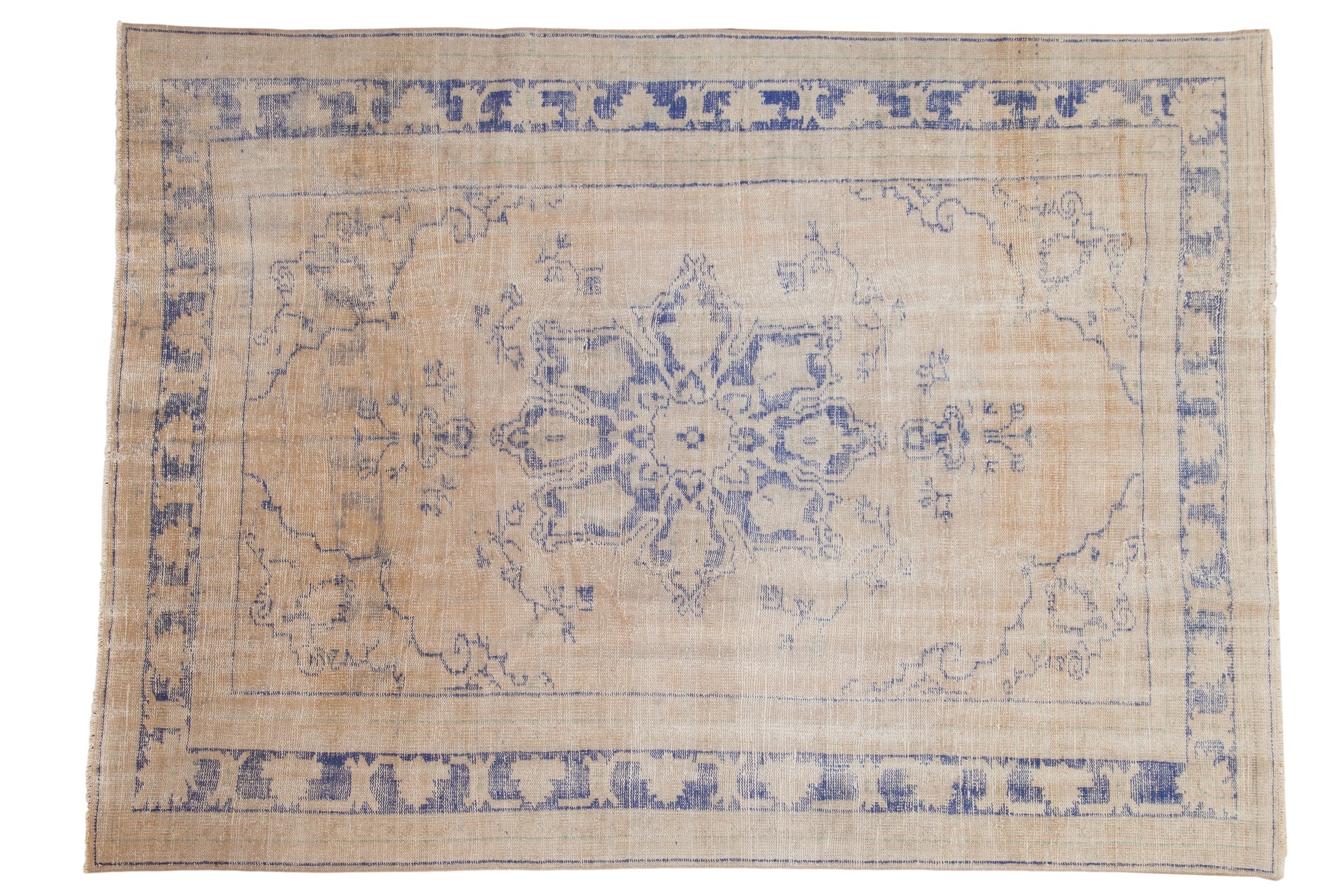 Distressed vintage Oushak carpet: faded cobalt blue starburst medallion on antique ivory field.