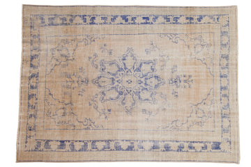 Distressed vintage Oushak carpet: faded cobalt blue starburst medallion on antique ivory field.