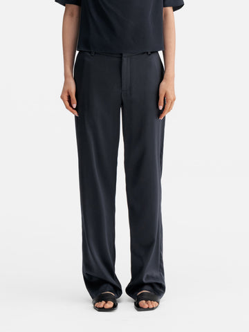 Model wearing Ahlvar Gallery Ava satin silk trousers blue grey