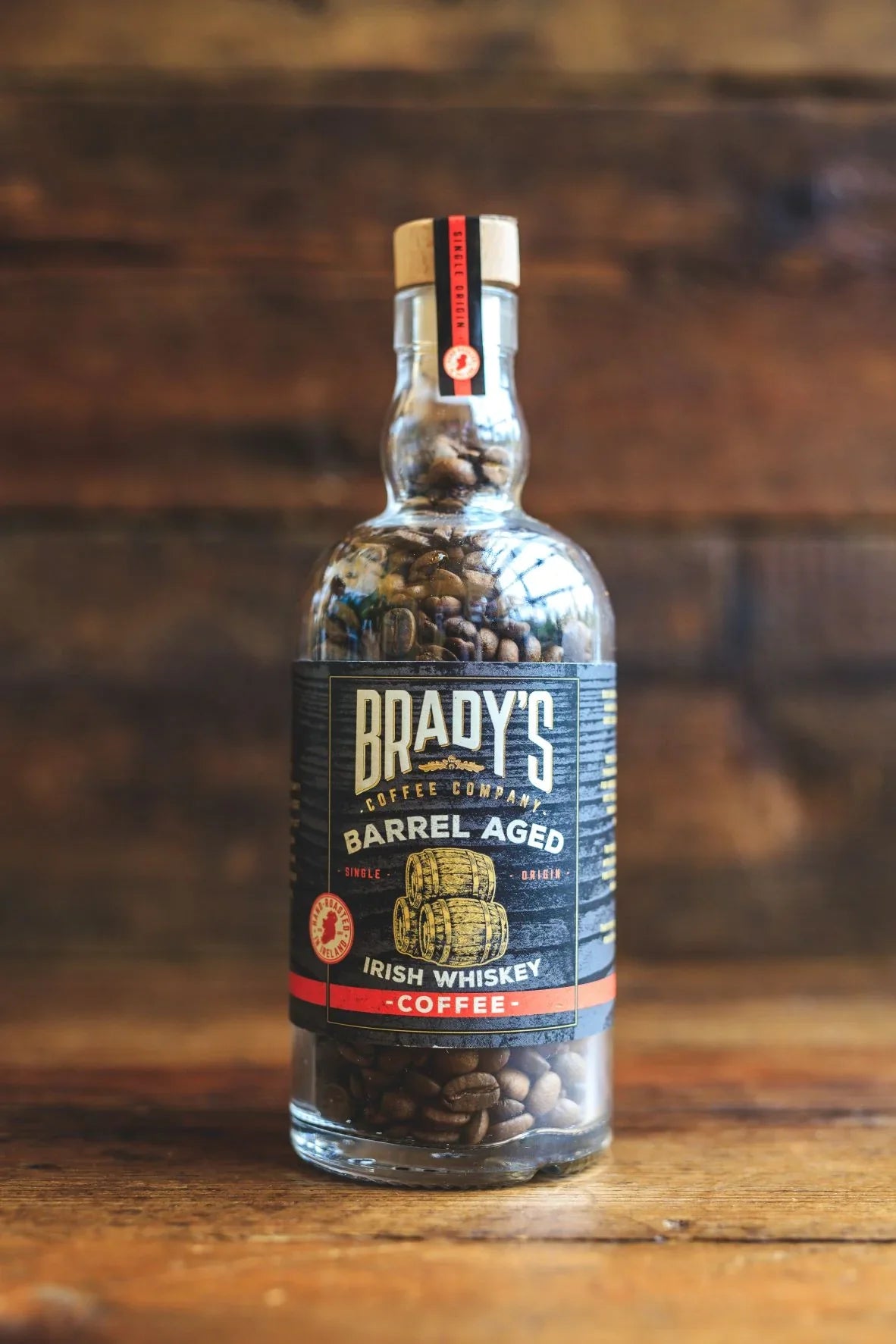 Bottle of Brady's Barrel Aged Irish Whiskey Coffee on a wooden surface with a wooden background