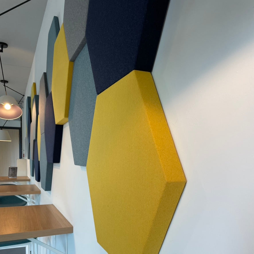 Hexagon akoestische wandpanelen in geel en antraciet gemonteerd in horecaomgeving