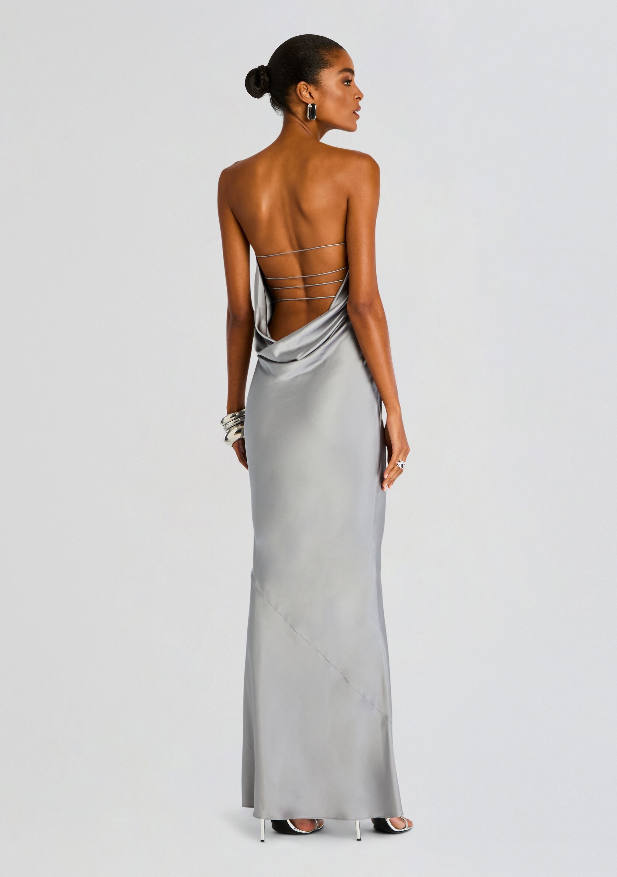 Back view of a silver satin gown with a draped low back and multiple thin back straps.
