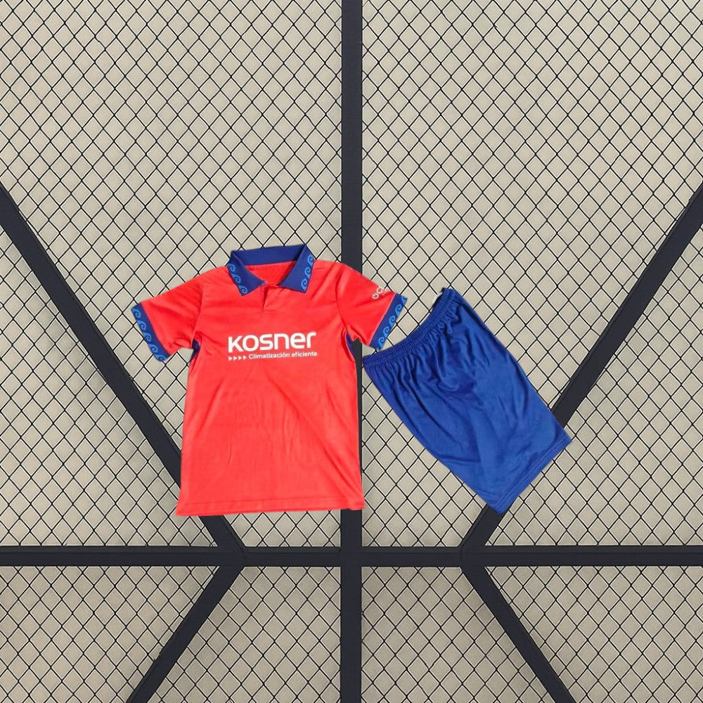 Equipación infantil Osasuna 26-27 local con camiseta roja de cuello polo y detalles azules, acompañada de pantalón corto azul