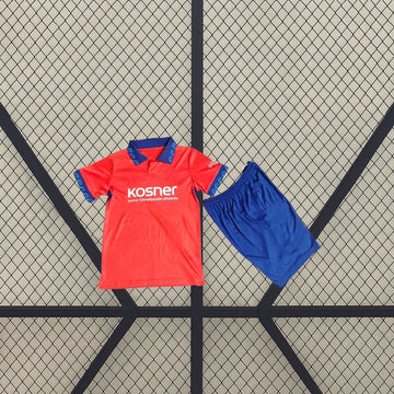 Equipación infantil Osasuna 26-27 local con camiseta roja de cuello polo y detalles azules, acompañada de pantalón corto azul