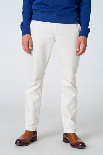 Pantalon blanc de Le Fabuleux Marcel de Bruxelles, vu de derrière, avec des chaussures marrons et un pull bleu.