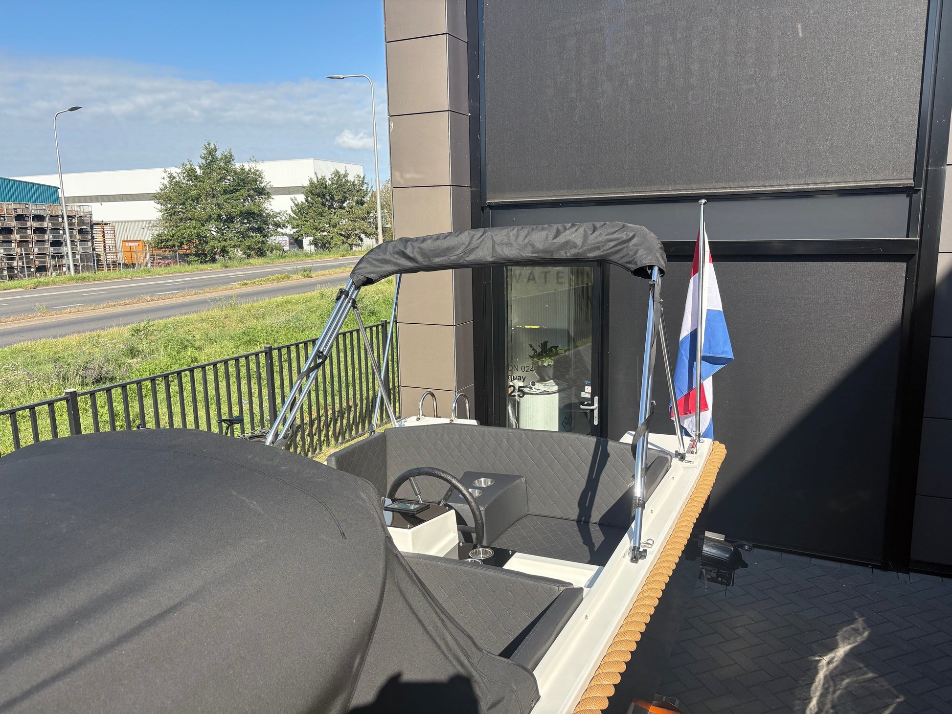Achteraanzicht van Marinaut 485 sloep met Nederlandse vlag en cabrioletkap, perfect voor recreatief varen.
