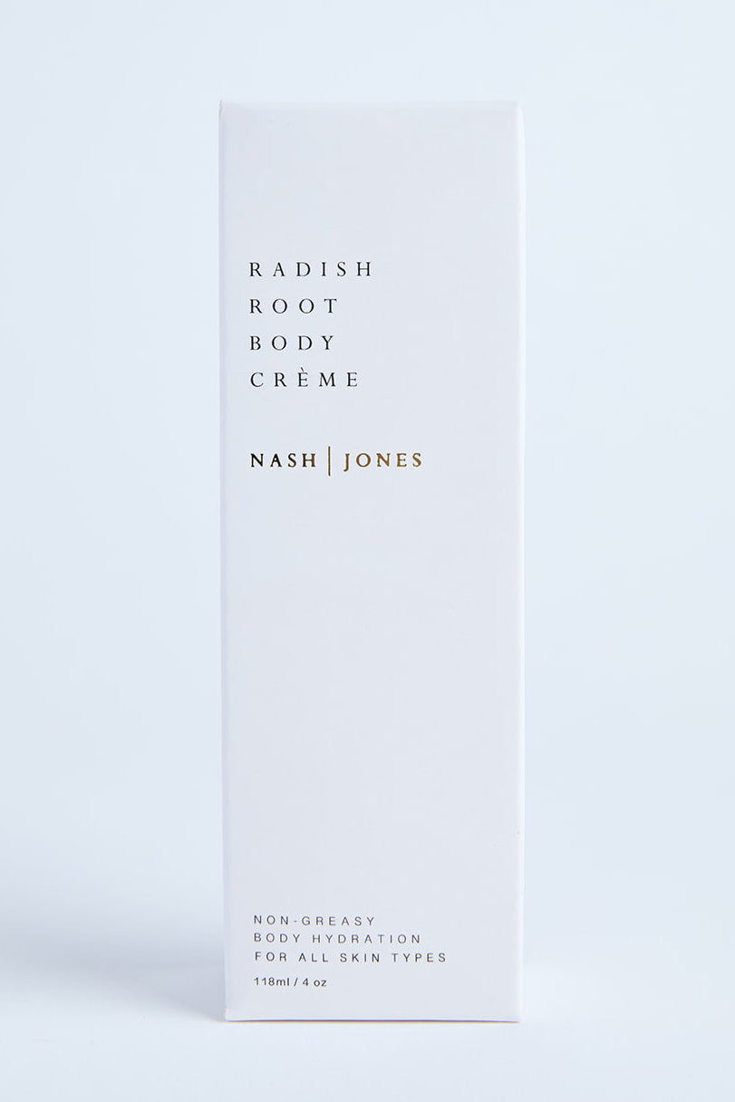 A white bottle of Nash & Jones Radiant Body Crème standing against a light background, with minimalistic design and a faint citrus/grapefruit scent indicated on the bottle.
