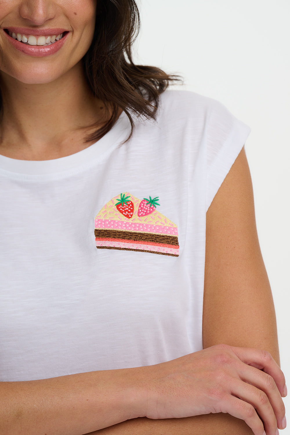 Woman wearing a white t-shirt with a colorful strawberry design on a plain background