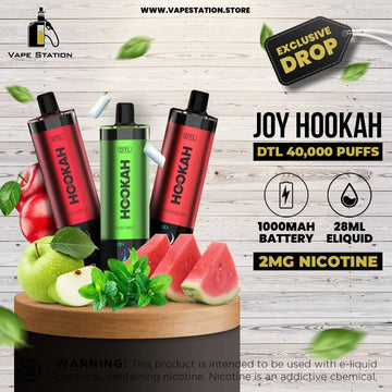 Joy Hookah vape devices with fruit and leaves on a wooden platform, branded as Vape Station.