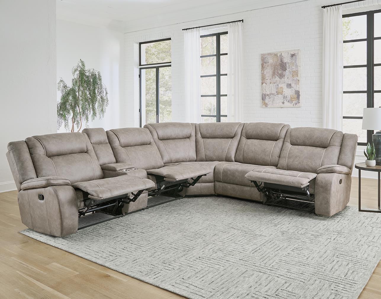 A desert taupe 6-piece modular reclining sectional sofa in a living room setting with a left-arm facing recliner, a right-arm facing recliner, an armless recliner chair, an armless chair, and a storage console.