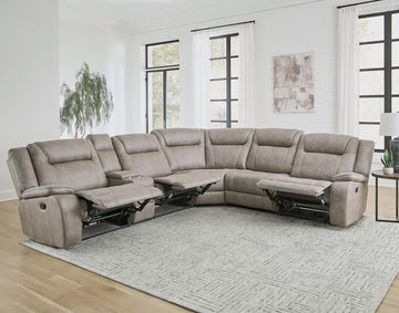 A desert taupe 6-piece modular reclining sectional sofa in a living room setting with a left-arm facing recliner, a right-arm facing recliner, an armless recliner chair, an armless chair, and a storage console.