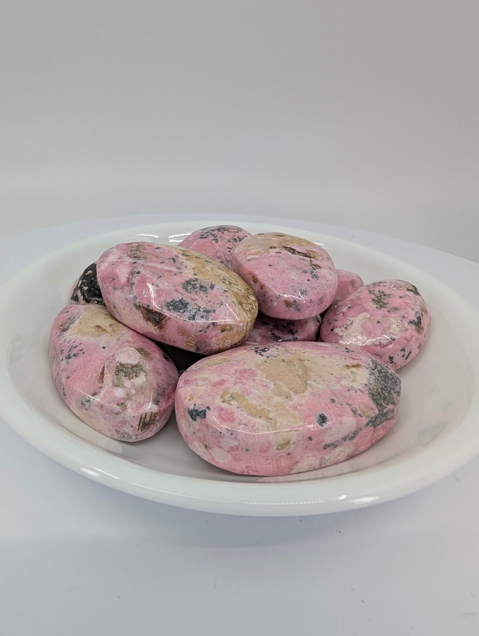 AA grade Pink Rhodonite tumbled stones from Peru displayed in a bowl showing rich pink color and soft mottling