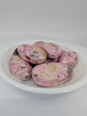 AA grade Pink Rhodonite tumbled stones from Peru displayed in a bowl showing rich pink color and soft mottling