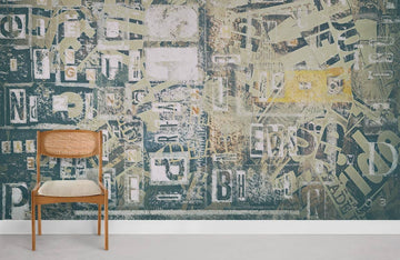 Vintage Typography Collage Mural Wallpaper in Rustic Green Tones, wooden chair, minimalistic room decor.